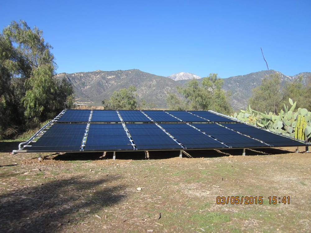 A large ground-mounted solar collector array against the foothills