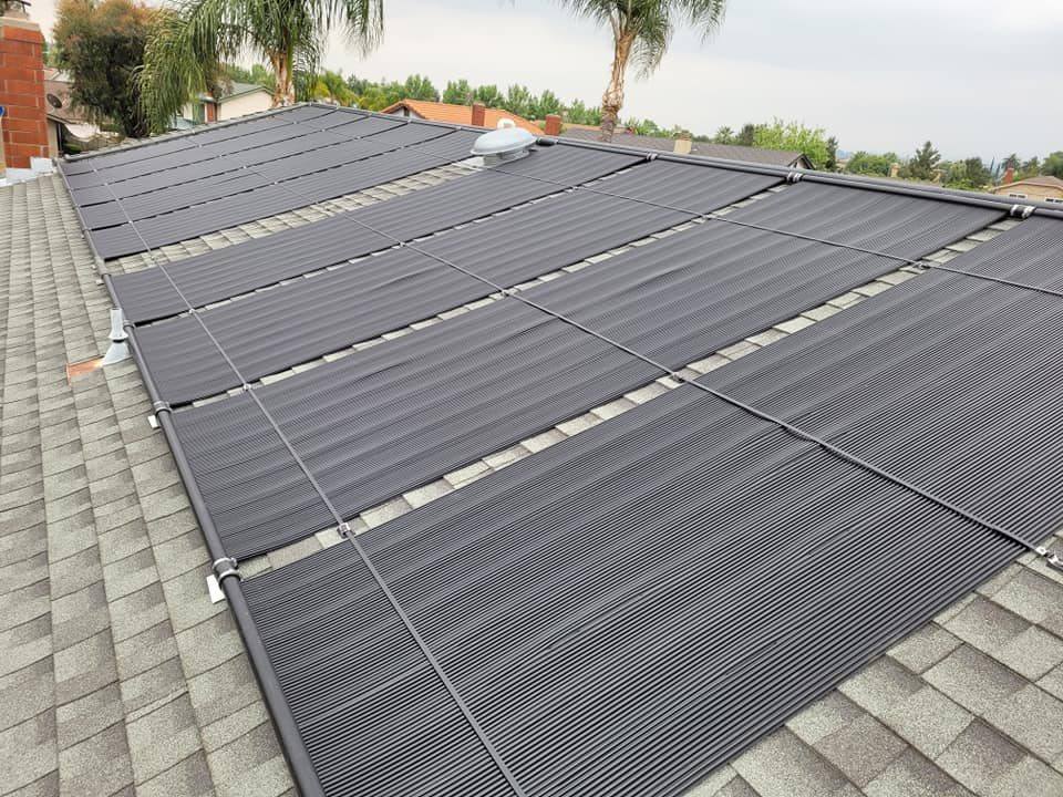 Rows of black solar pool heating collectors mounted across a composition shingle roof