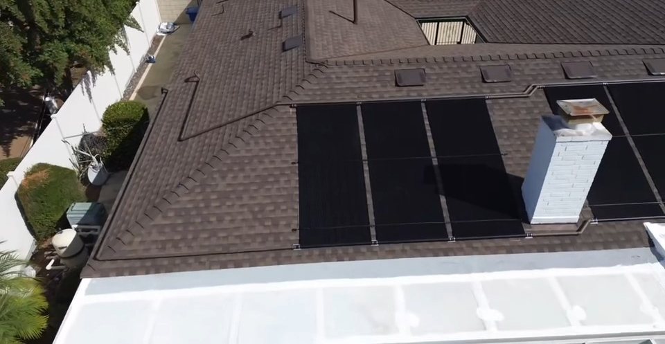 Aerial view of the same shingle roof after installation, now carrying a black solar pool heating collector array