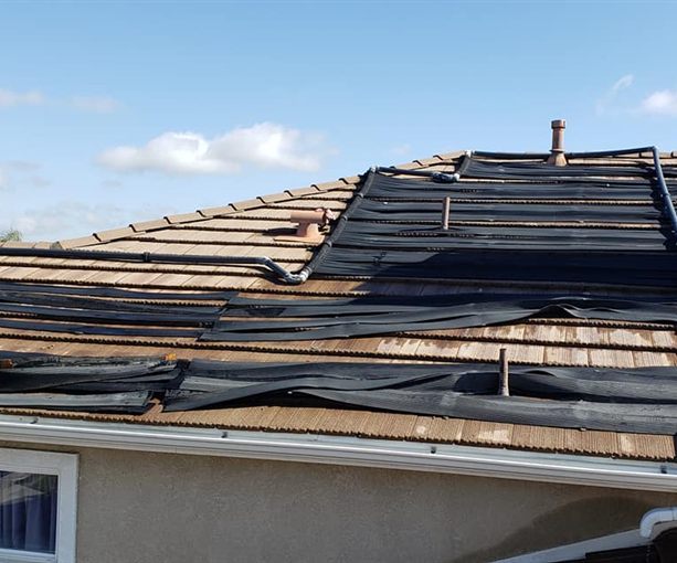 Buckled rubber mat solar panels lifting off a tile roof, ready for replacement